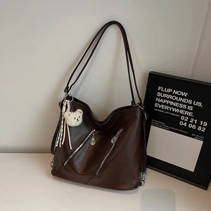 Détail d'un sac cabas marron foncé avec fermetures éclair et charm ourson en peluche