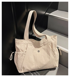 Detail of off-white large tote bag featuring drawstring side pockets and metal logo