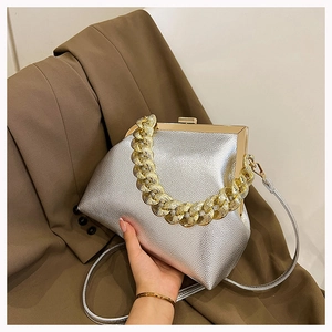 Close-up of silver textured leather handbag with gold chain handle and metal frame closure