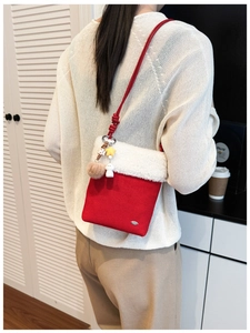 Detail of red crossbody bag with white faux shearling trim and cute plush pendants