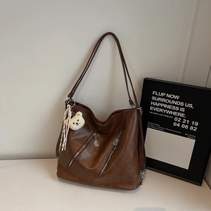 Détail du sac cabas rétro marron foncé avec fermetures éclair diagonales et pendentif ours