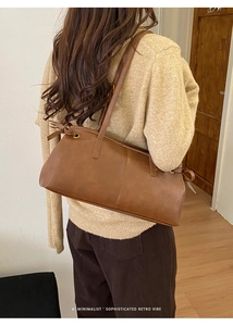 Close-up of a vintage brown leather shoulder bag with vertical stitching and drawstring details