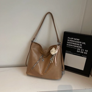 Détail d'un sac en cuir PU marron avec fermetures éclair argentées et un charm d'ours blanc