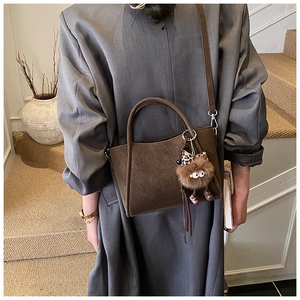 Detail view of a vintage dark brown bucket bag with adjustable strap and plush charm