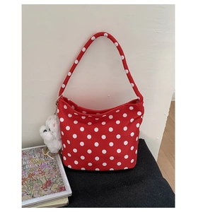 Détail d'un sac rouge à pois avec un joli pendentif chiot en peluche blanc sur le côté