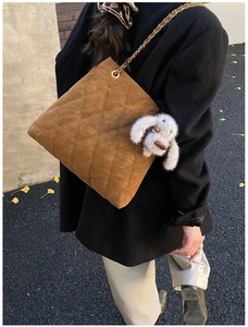 Detail van bruine gewatteerde shopper met gouden ketting en pluchen konijnenhanger
