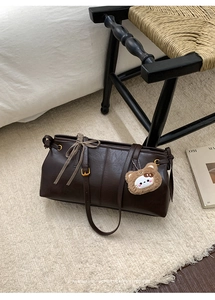 Close-up of retro brown tote bag with ribbon bow and cute teddy bear charm