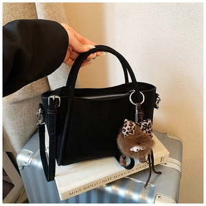 Detail of black bucket bag with plush leopard monster charm and silver hardware