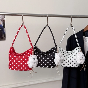 Détail de trois sacs sous les bras à pois en rouge, noir et blanc avec breloques de chat