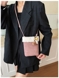 Detailed shot of pink crossbody bag with white faux fur trim and cute charms in a lifestyle setting
