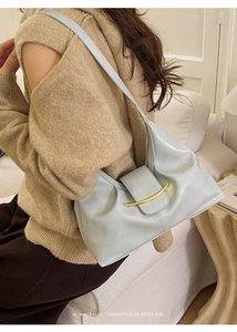 Détail du sac baguette rétro bleu menthe avec garniture dorée et texture plissée