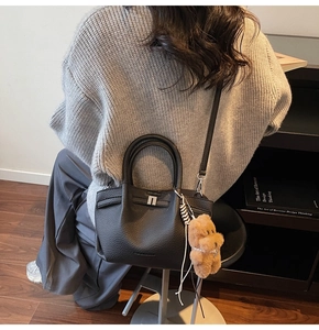 Détail du sac seau en cuir grainé noir avec charme ours en peluche marron et logo