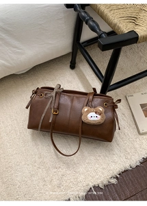 Close-up of brown retro tote bag with teddy bear charm and plaid ribbon detail