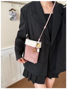 Detailed shot of pink faux suede crossbody bag with soft white faux fur trim and cute charms