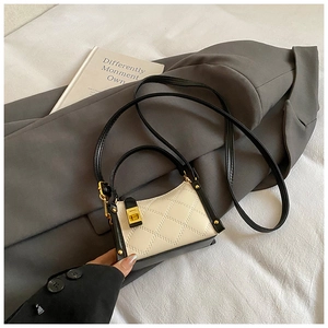 Detailed view of quilted faux leather handbag with golden twist lock on grey suit fabric
