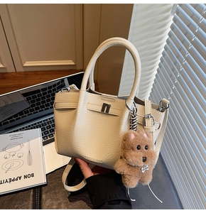 Détail d'un sac seau en cuir grainé beige avec un pendentif chien en peluche mignon