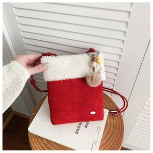 Close-up of red suede crossbody bag with white faux fur trim and beaded pompom charm