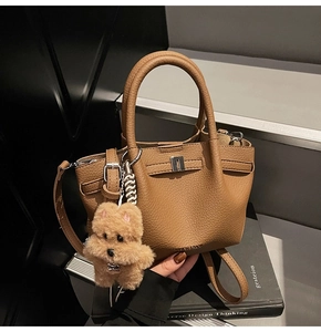 Détail de la texture cuir litchi marron et du fermoir en métal argenté sur le sac à main