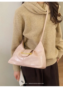 Détail du sac baguette rétro rose pâle avec texture cuir brillant et garniture dorée