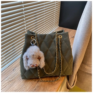 Detail van een gewatteerde shopper met gouden ketting en pluche konijntje op een vensterbank