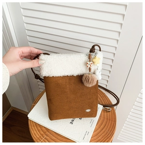 Close-up of brown suede crossbody bag with white faux fur trim and cute star charms