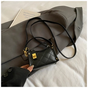 Detailed macro view of black quilted leather bag with elegant golden turn-lock closure