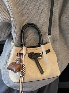 Chic beige canvas bucket bag with black leather trim and crossbody strap for women