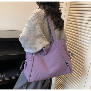 Detail of purple nylon tote bag featuring side pocket with black adjustable drawstring