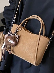 Retro brown crossbody bag with plush monster charm over a stylish black blazer outfit