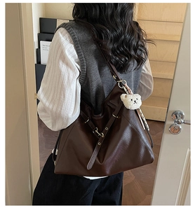 Detail of deep brown PU leather tote with a cute cream plush bear charm and metal eyelets