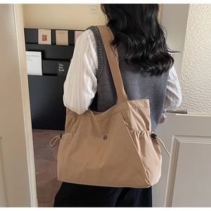 Detail view of khaki large capacity tote bag with drawstring side pockets and snap button