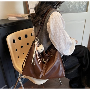 Close-up of a vintage brown leather backpack with gold buckle and teddy bear charm accessory