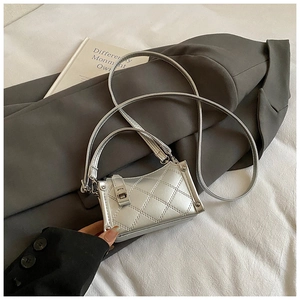 Detail of silver metallic mini bag with quilted stitching on a gray suit jacket