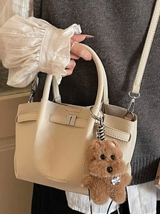 Sac seau chic en cuir beige avec poignées et un adorable pendentif chien en peluche