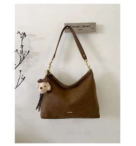 Detail view of brown faux leather shoulder bag with a cute plush bear charm accessory