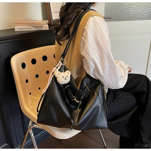 Detailed shot of large black tote bag with plush bear charm and woven ribbon accessory