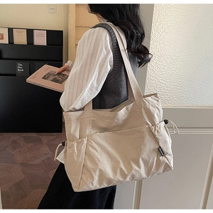 Detailed side view of a large beige canvas tote bag with drawstring pocket and black label