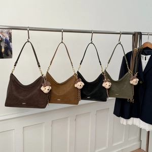 Detail view of four minimalist crescent shoulder bags in multiple colors with bear charms
