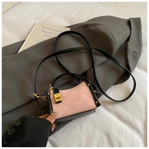 Detail of pink and black quilted crossbody bag with gold twist lock and leather handle