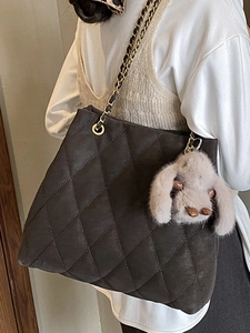 Sac cabas matelassé avec bandoulière chaîne et charme lapin en peluche porté par un mannequin