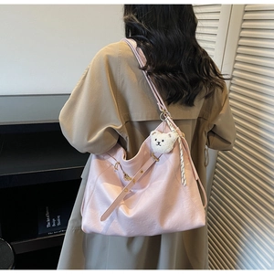 Pink faux leather tote bag detail with golden metal buckle and white plush bear charm