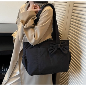 Detail of black bow tote bag with side drawstring pocket and spacious nylon design