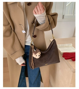 Detail of vintage brown suede shoulder bag with cute leopard bow bear plush keychain