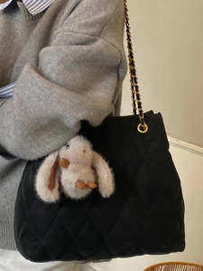 Sac cabas matelassé avec chaîne dorée et charm lapin en peluche porté à l'épaule