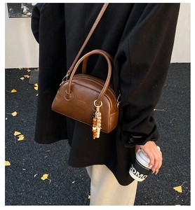 Détail d'un sac oreiller en cuir marron vintage avec pendentif en perles colorées sur bandoulière