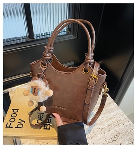 Detail of vintage brown leather bucket bag with fashion print and plush sheep charm