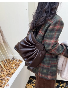 Détail d'un sac cabas en cuir plissé marron foncé montrant la texture et le logo rétro