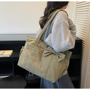 Detail of olive green tote bag with large decorative bow and elegant quilted pattern