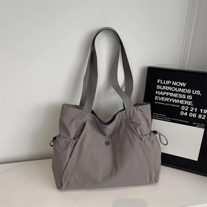 Detail of minimalist dark grey nylon tote bag with drawstring pockets and metal logo