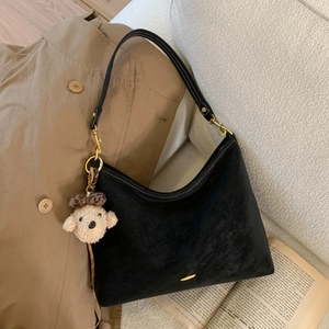 Detail of black suede hobo bag with contrast stitching and cute plush puppy charm